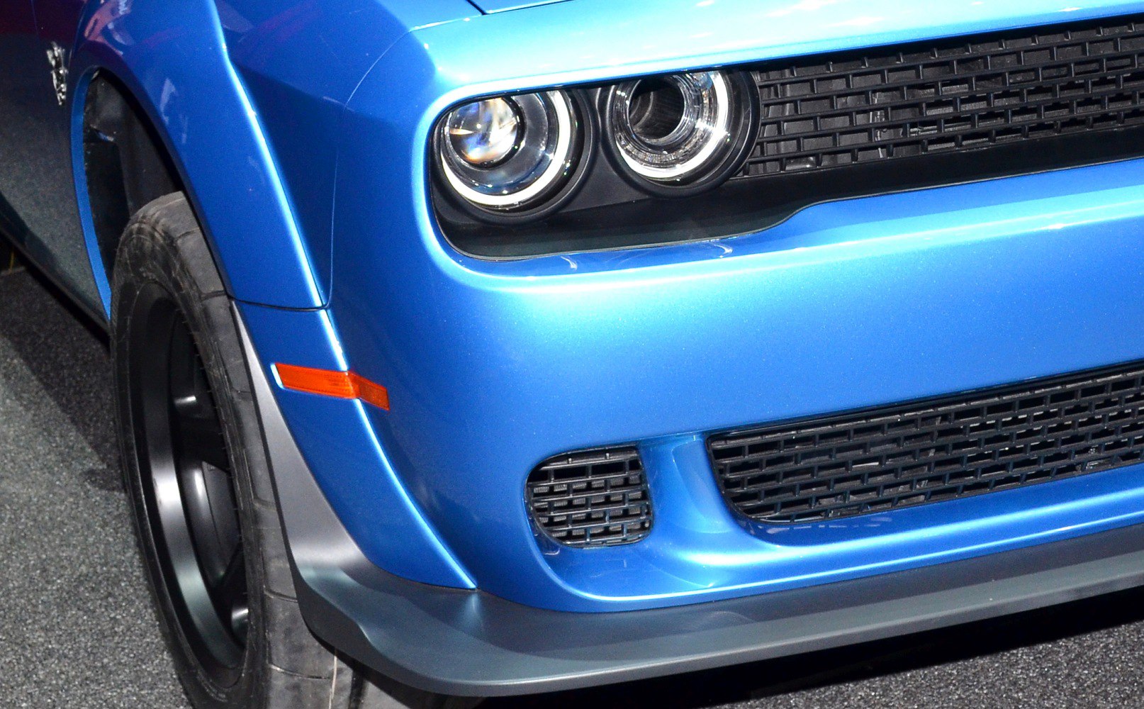 Front headlight, grille, and wheel close-up of blue muscle car