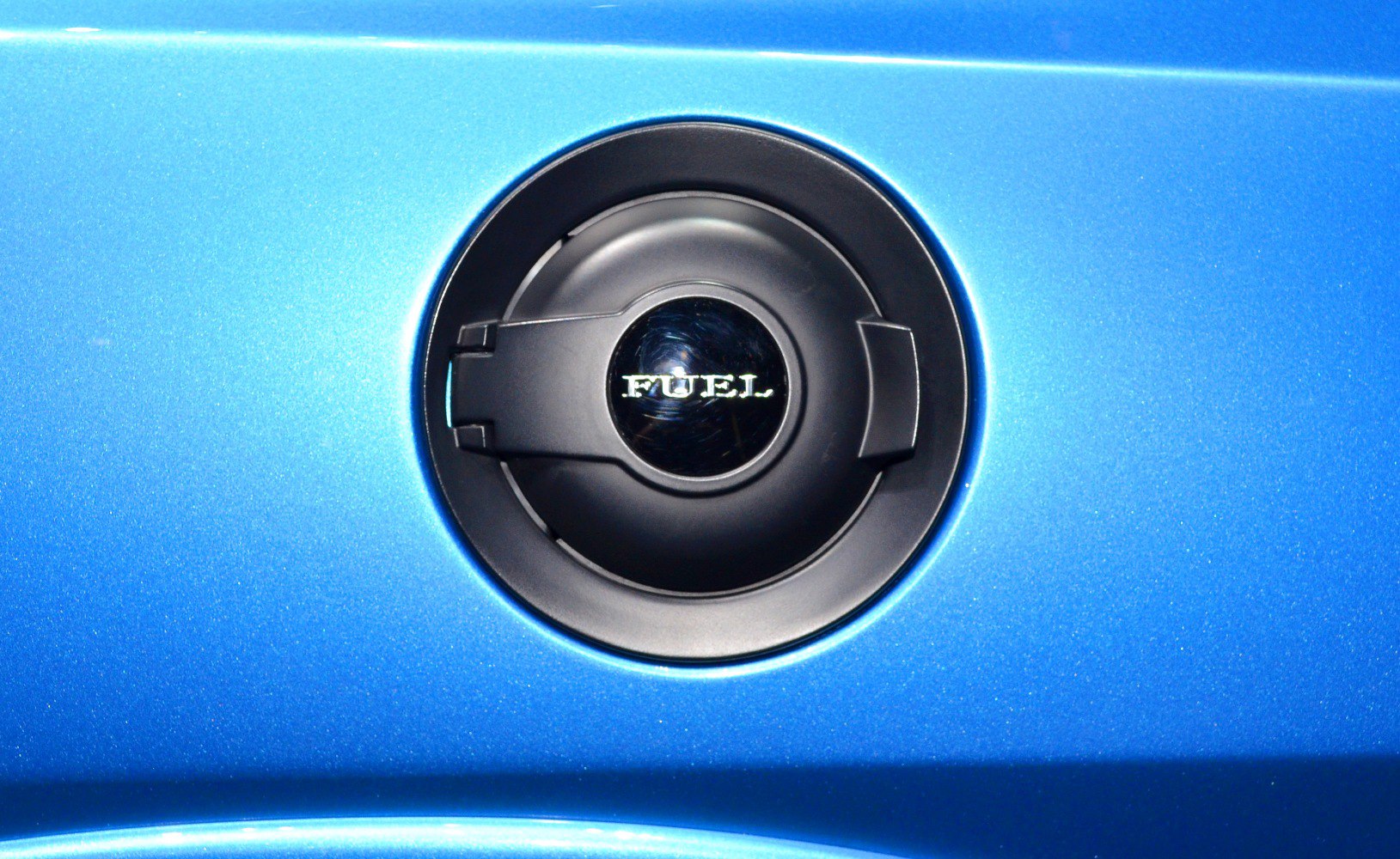 Close-up of black fuel cap on blue painted body