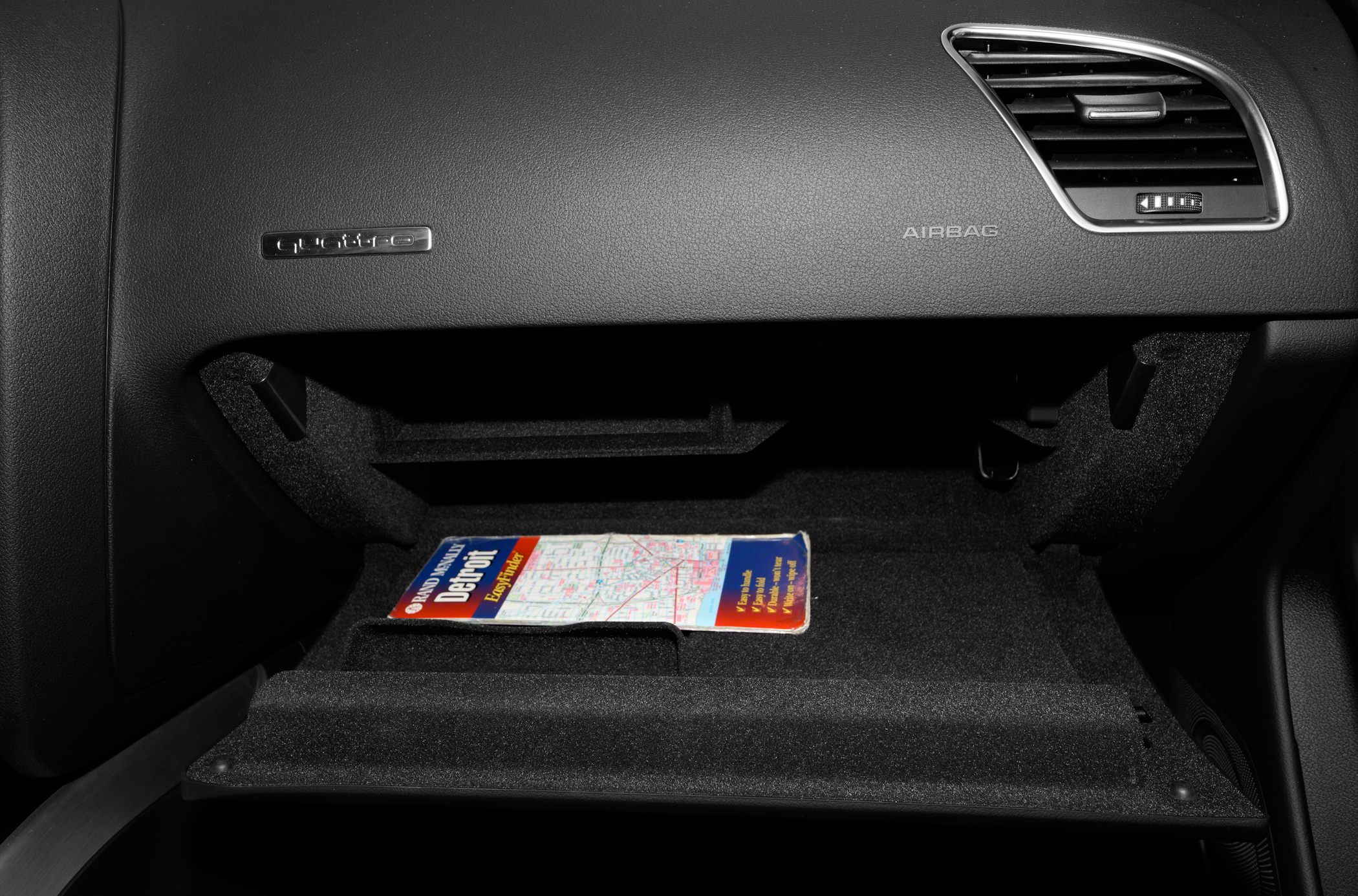 Open glove compartment with a map and dashboard vent details