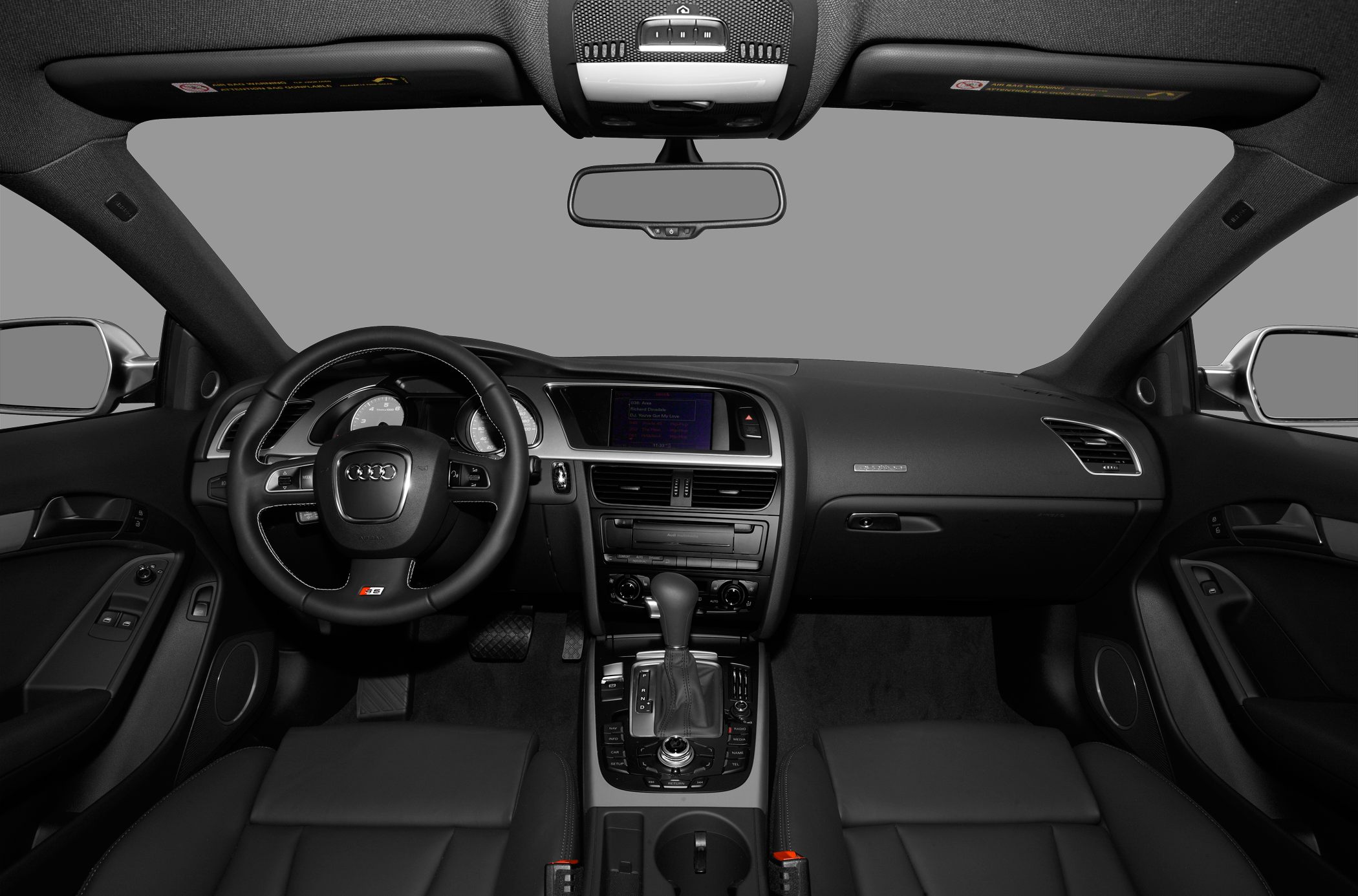 Car interior with steering wheel, dashboard, infotainment screen, and center console.