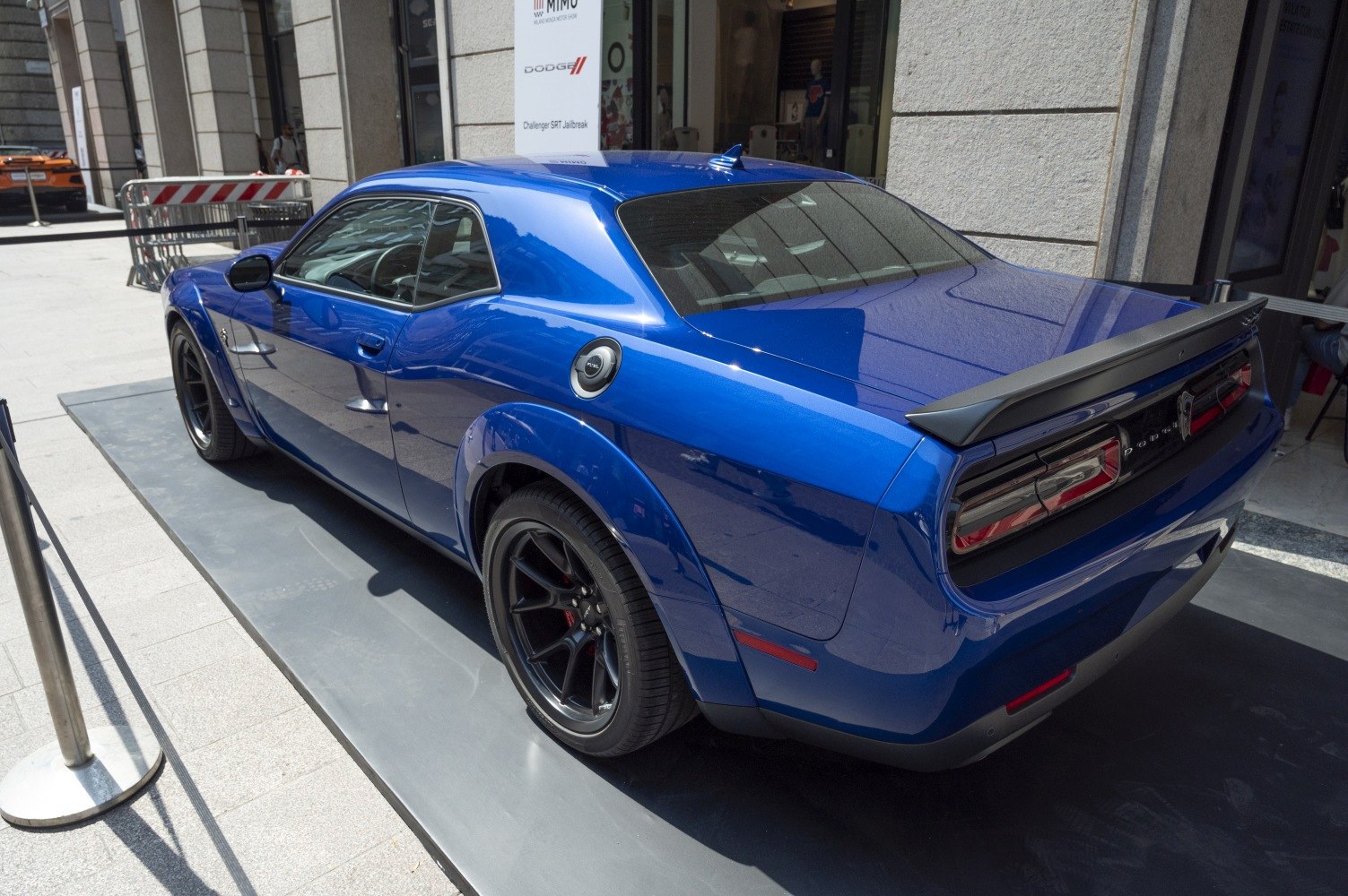 Rear side view of blue muscle car with widebody fenders and rear spoiler