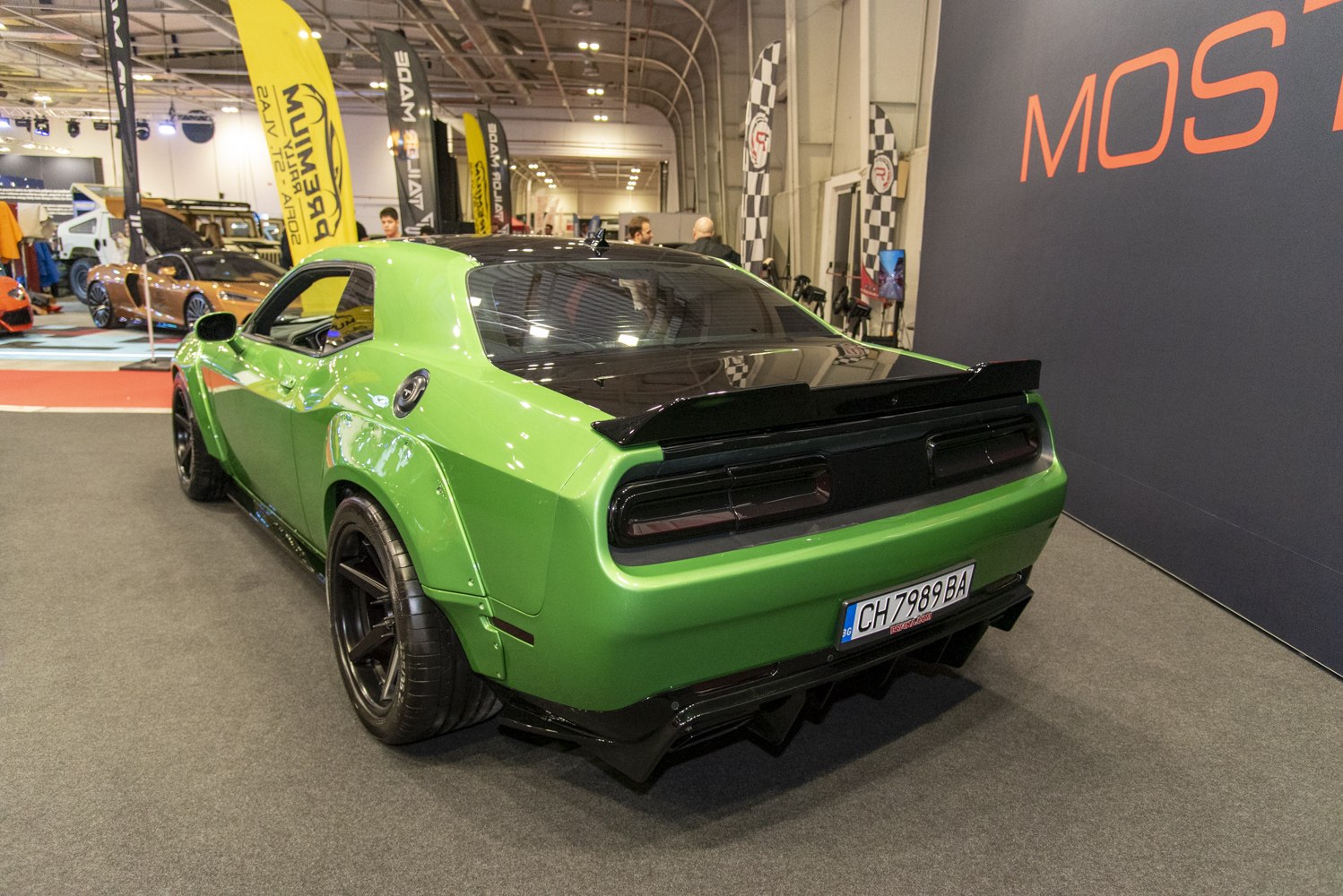 Green muscle car rear with wide fender flares and black spoiler