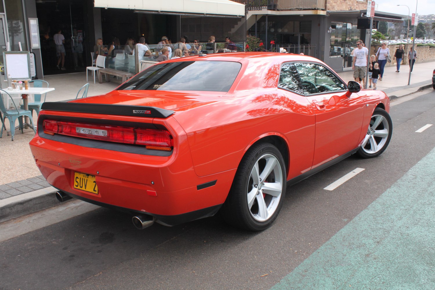 Rear and side view of a red muscle coupe with distinct taillights and dual exhaust