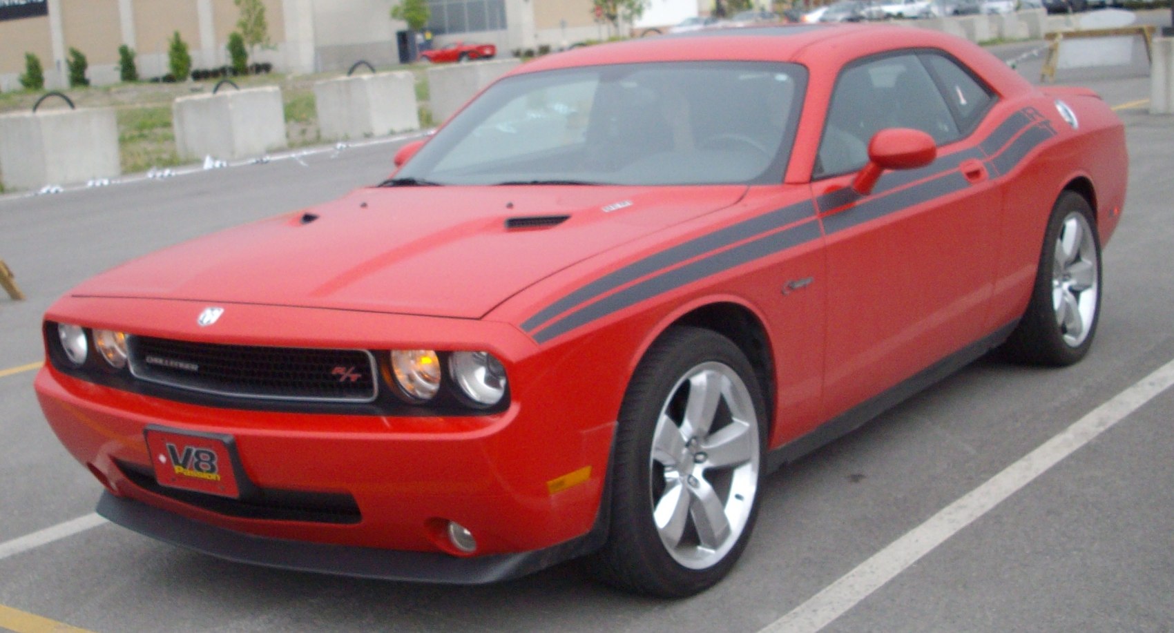 Red coupe with black racing stripes and V8 emblem front side view