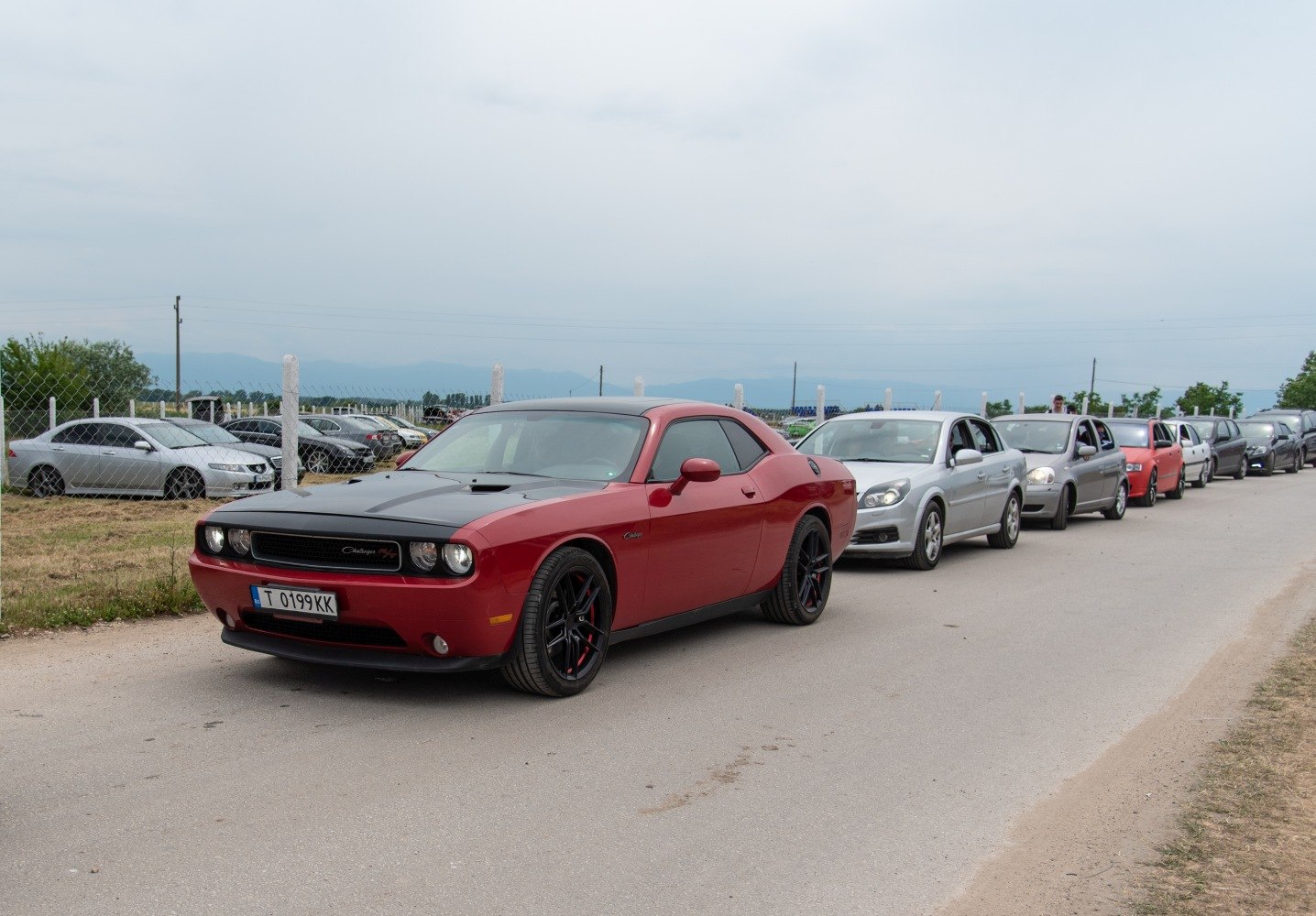 Red coupe with black hood, sporty black wheels, and aggressive front fascia