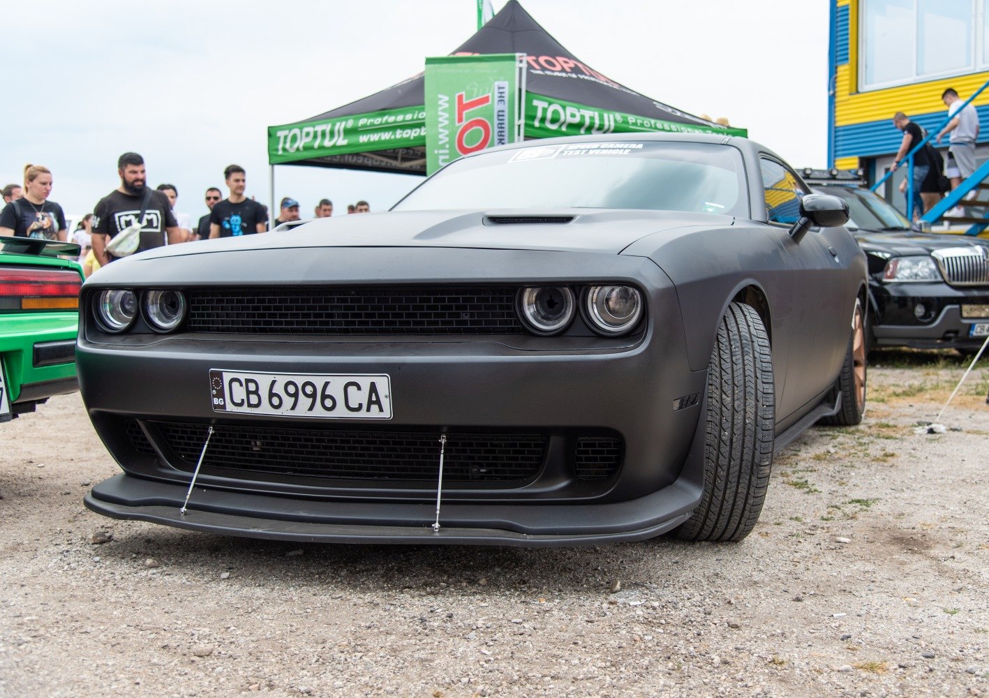 Front view matte black muscle car with aggressive grille and wide tires