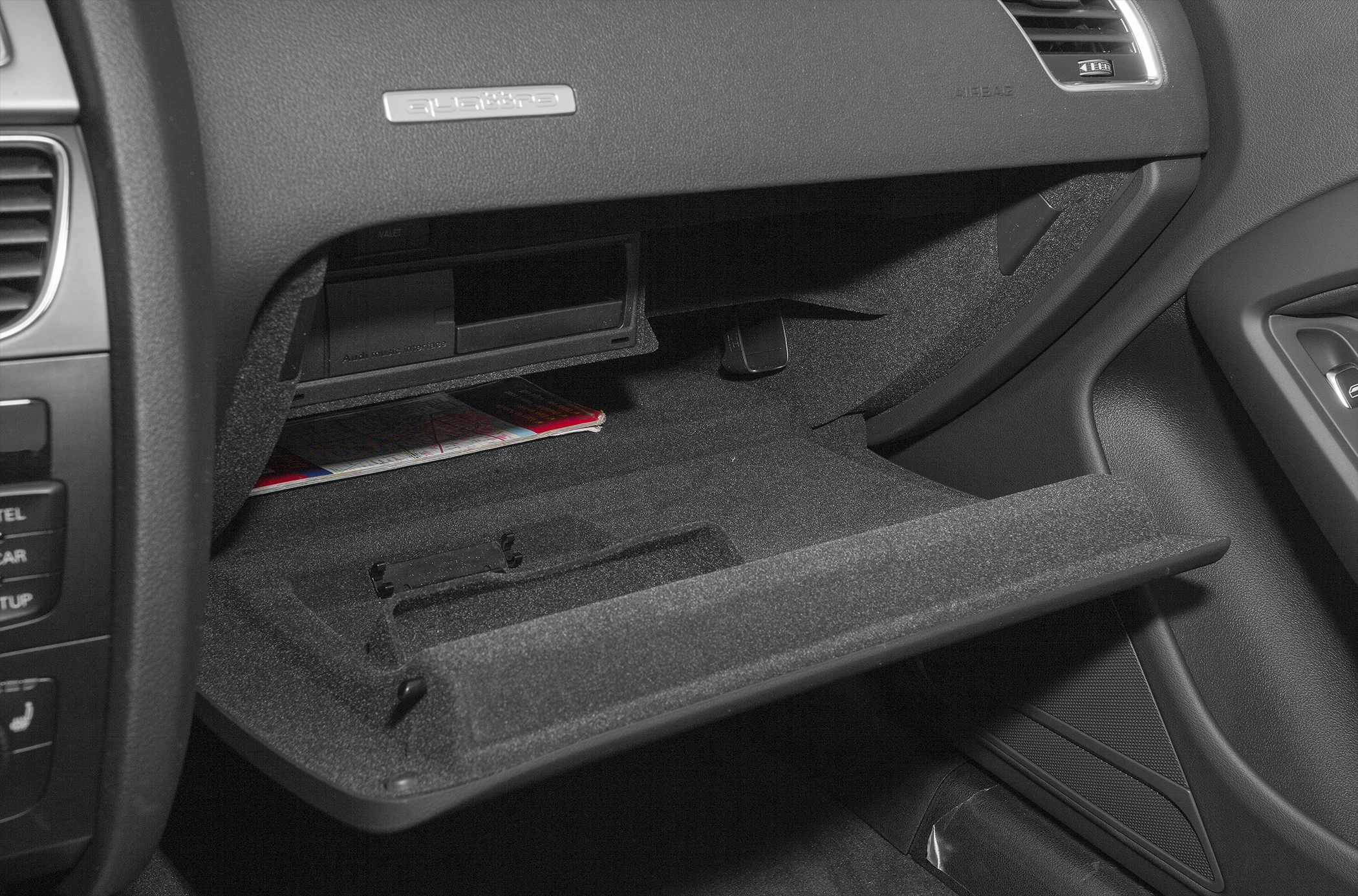 Open glove compartment with textured interior storage space.