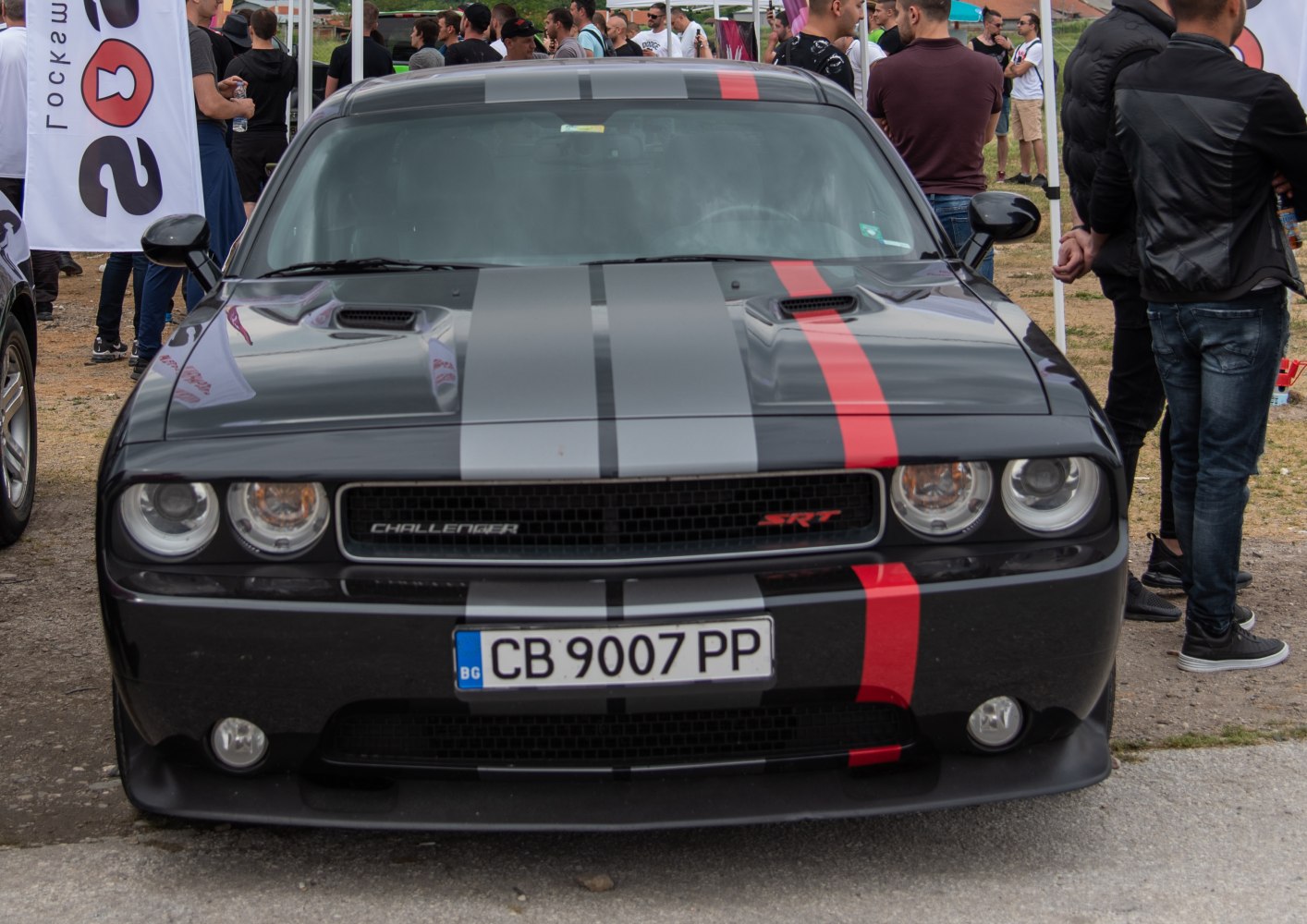 Front view of aggressive muscle car with distinctive racing stripes and hood scoops.