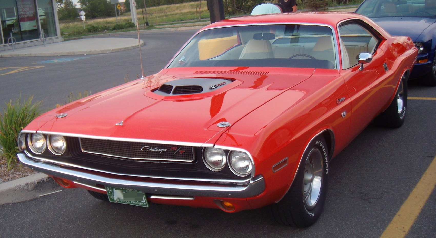 Muscle car front grille with quad headlights and a prominent hood scoop.