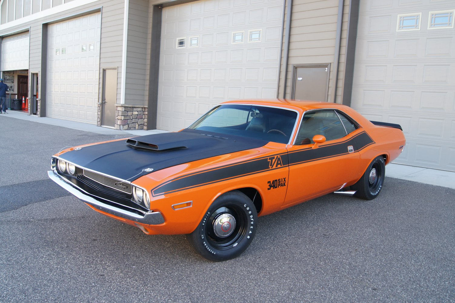 Orange classic muscle car with black hood scoop and side racing stripes