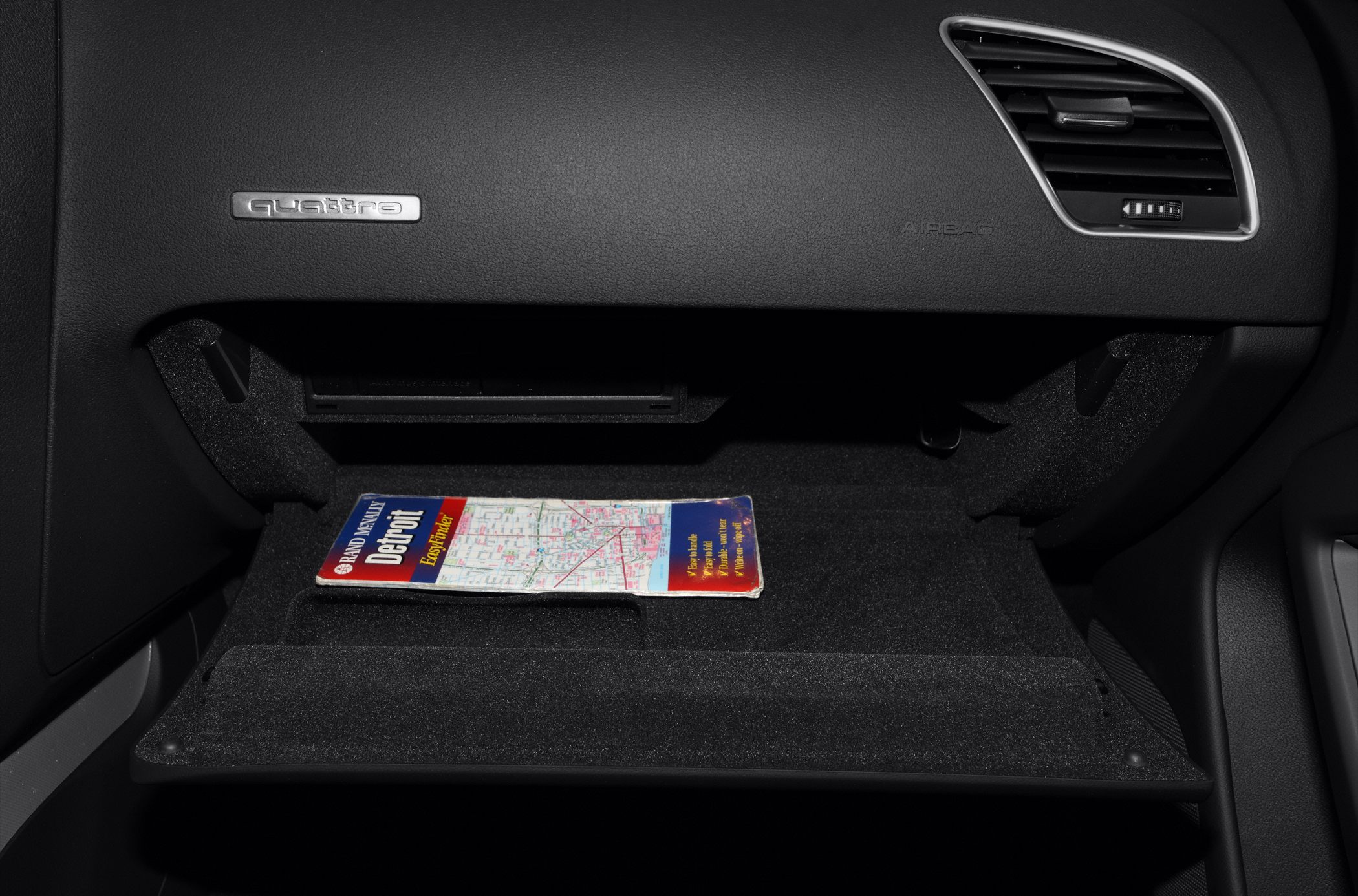Open glove compartment with map inside and quattro badge.