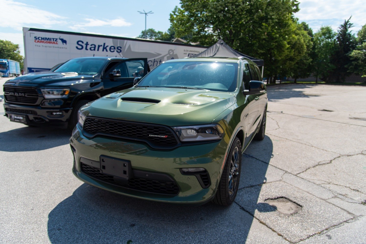 Green SUV front with hood scoop and mesh grille.