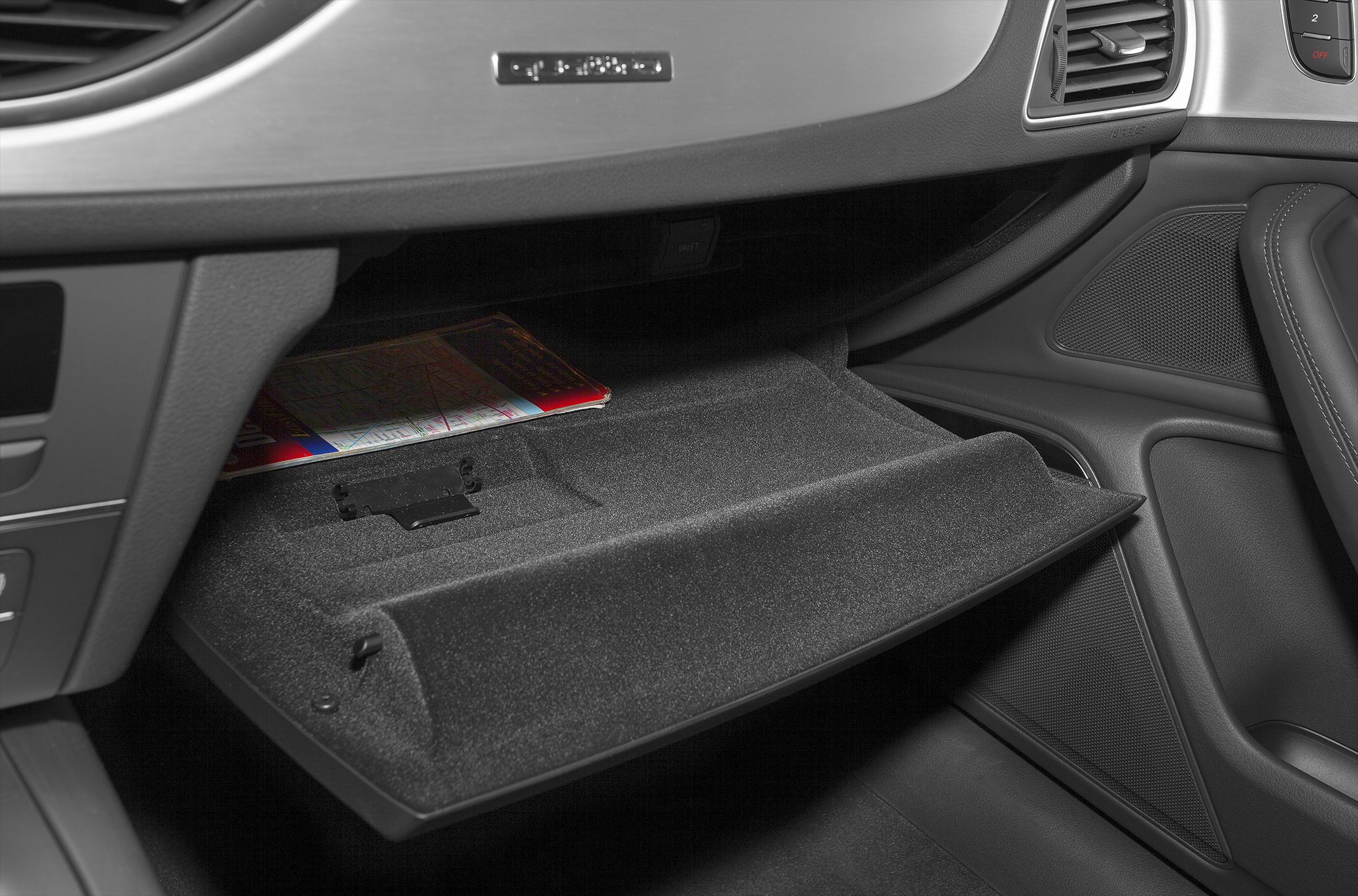 Open glove compartment with textured interior lining and document storage.