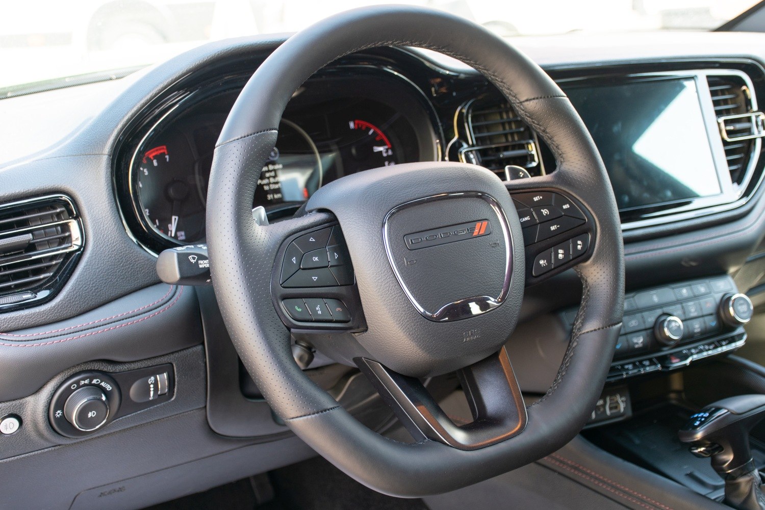 Steering wheel with control buttons and dashboard with instrument panel and infotainment screen
