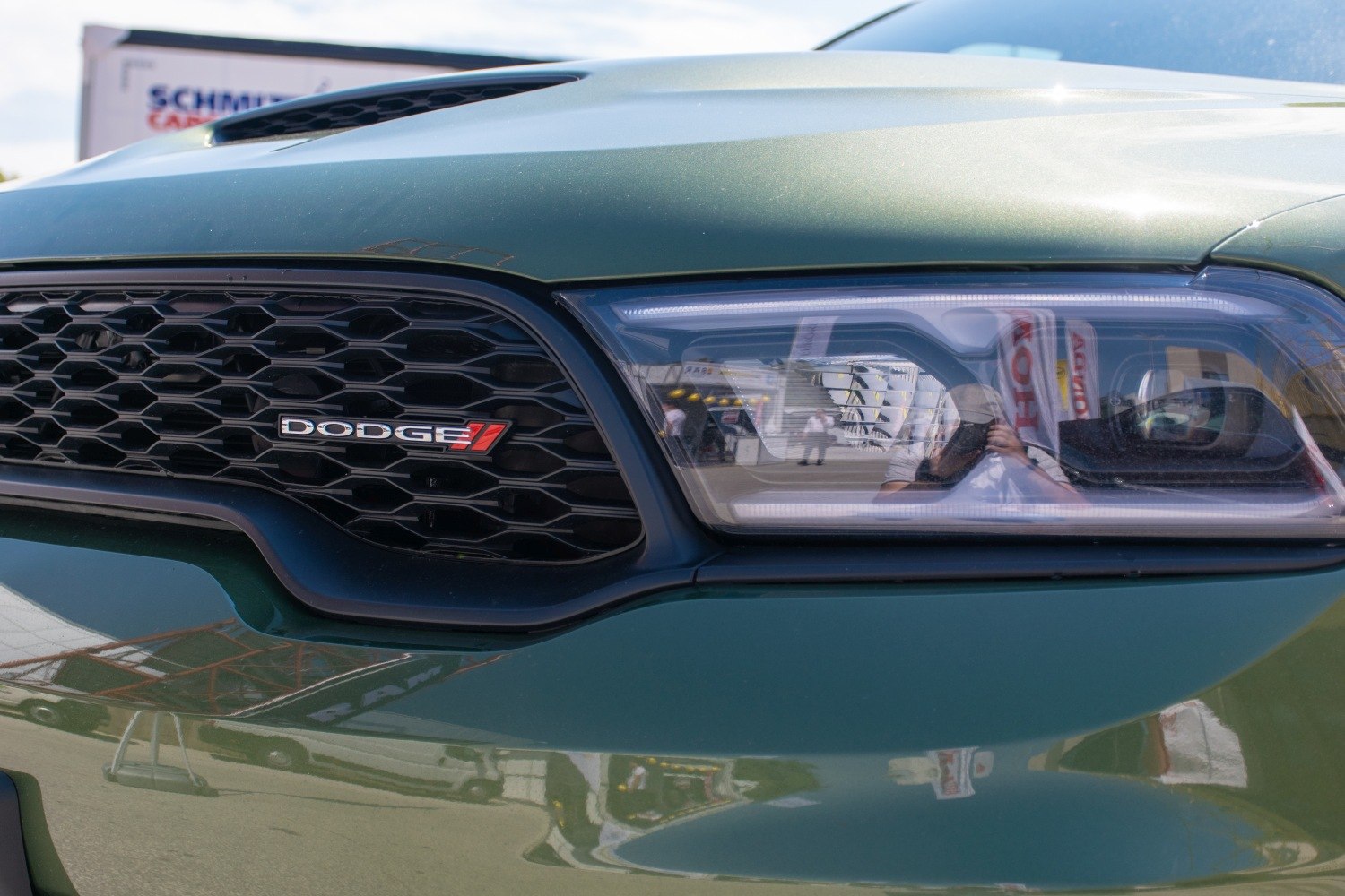 Close-up of modern LED headlight and black honeycomb grille with logo