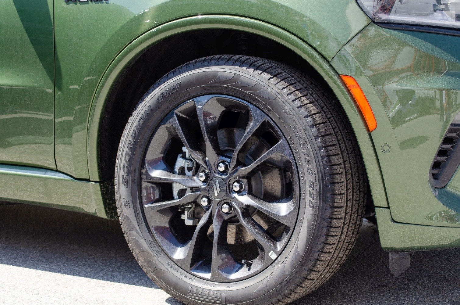 Black alloy wheel with Pirelli Scorpion Verde tire on a green vehicle