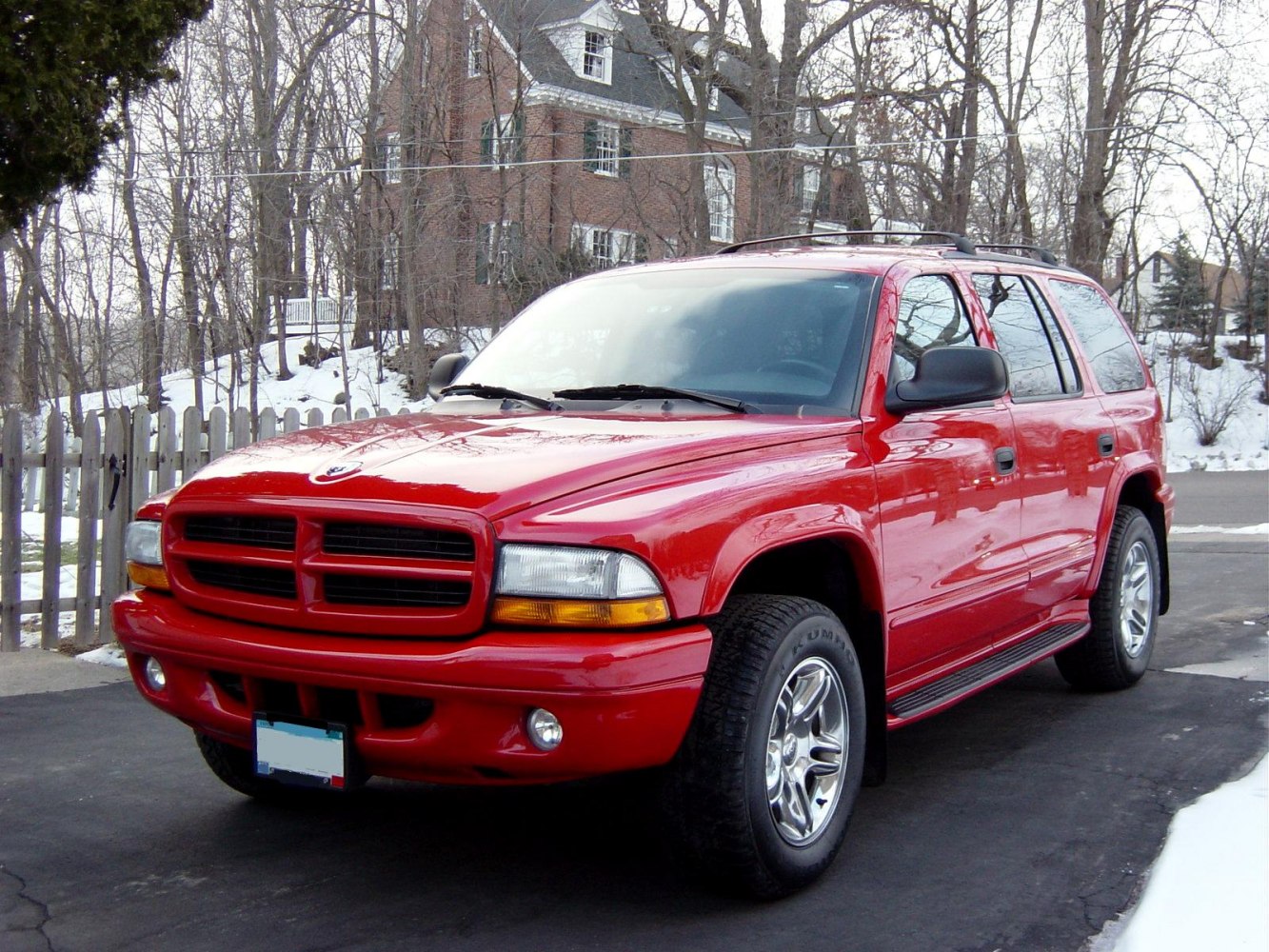 Robust red SUV front and side view with chrome wheels and roof rails