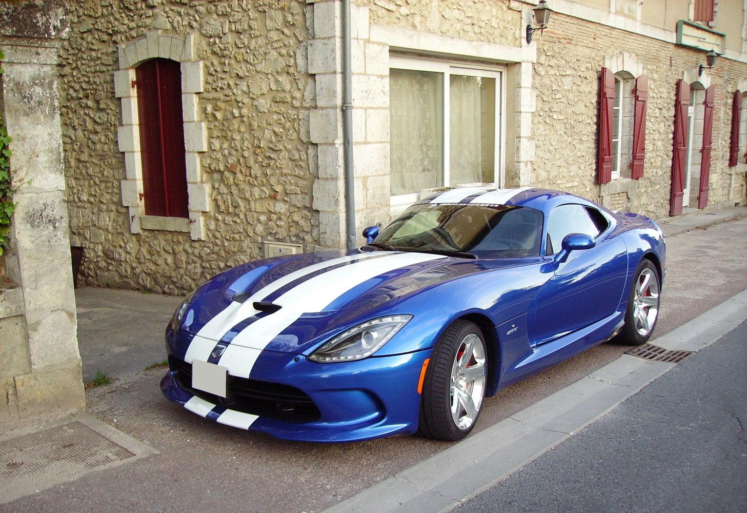 Blue sports coupe with white racing stripes and aerodynamic front