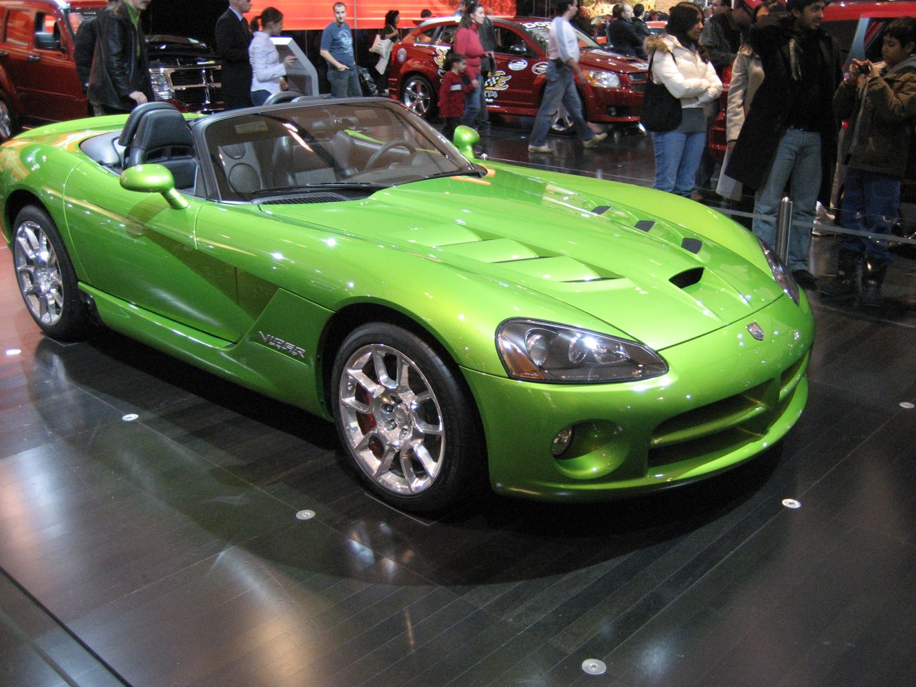 Convertible sports car with bright green color and prominent hood vents