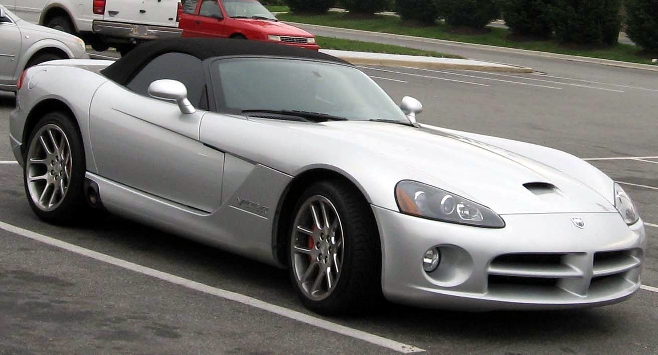 Silver convertible sports car with hood scoop and multi-spoke wheels
