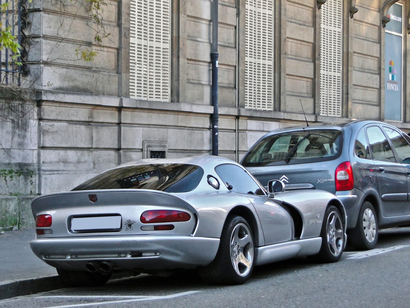 Sleek silver sports coupe rear view with distinctive taillights and dual exhausts
