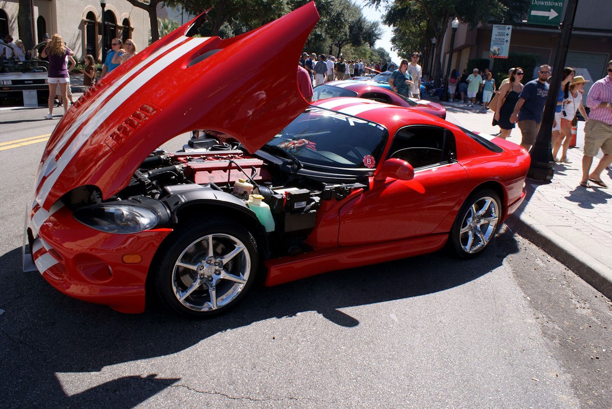 Red sports coupe with raised front hood showing engine