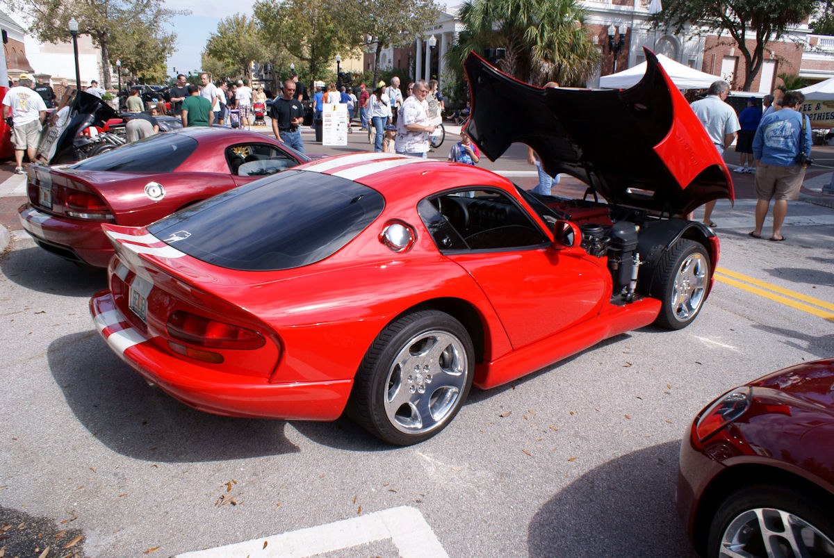 Red coupe with white racing stripes and raised front hood
