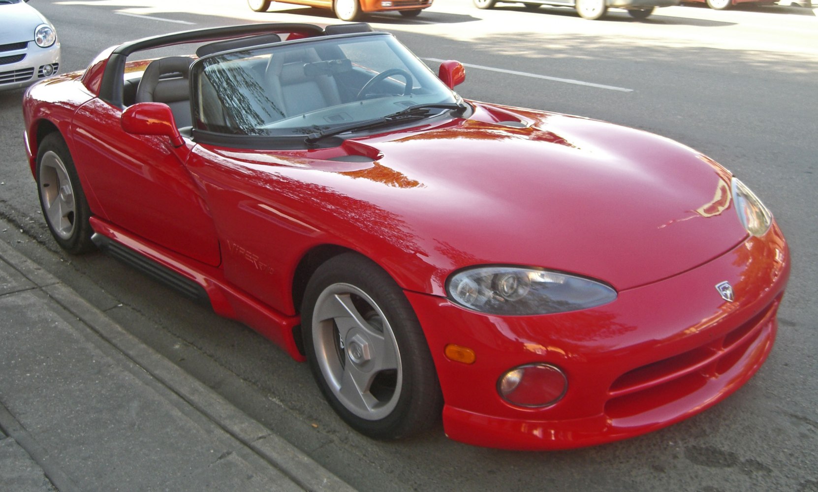 Red convertible sports car with hood vents and alloy wheels
