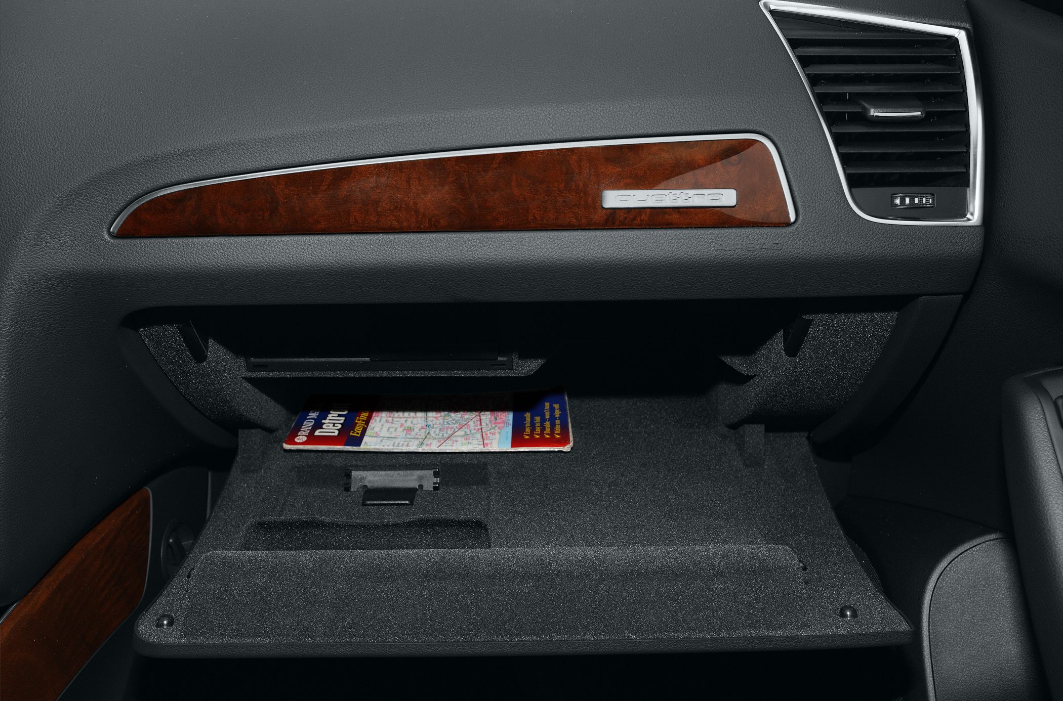Open glove compartment with wood trim and ventilation grill inside car interior