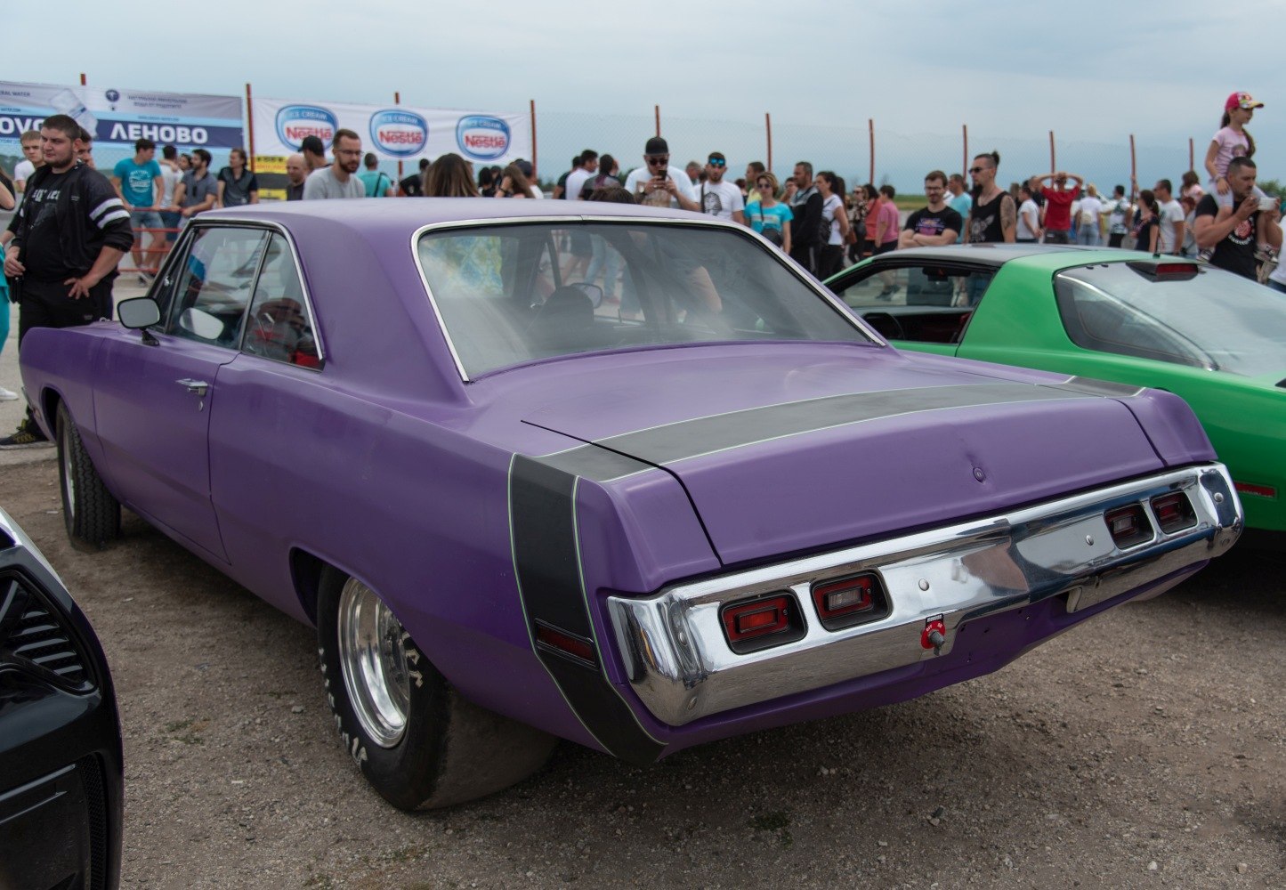 Purple vintage muscle car rear with wide drag racing tires and chrome bumper