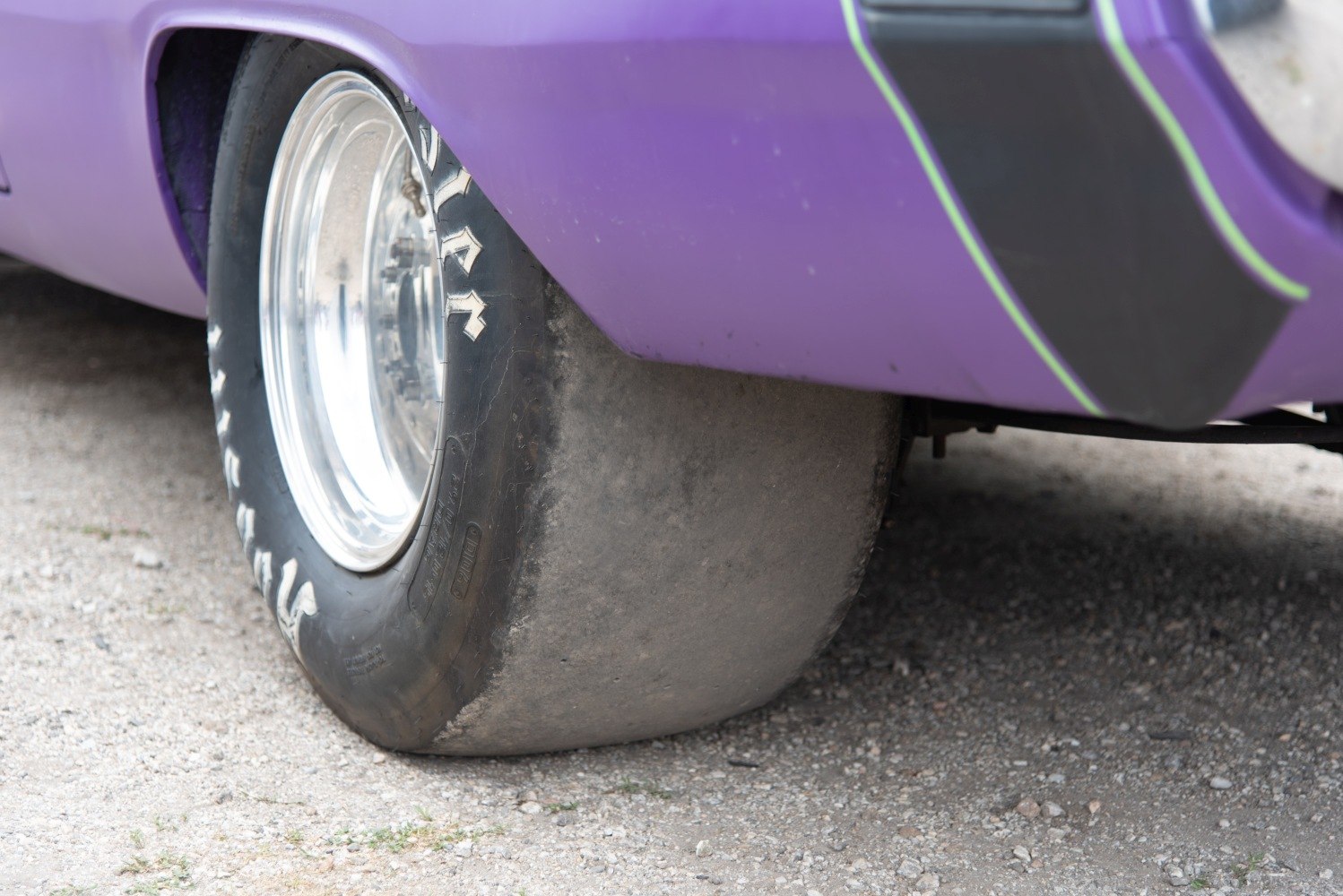 Wide drag slick tire and polished alloy wheel on classic muscle car