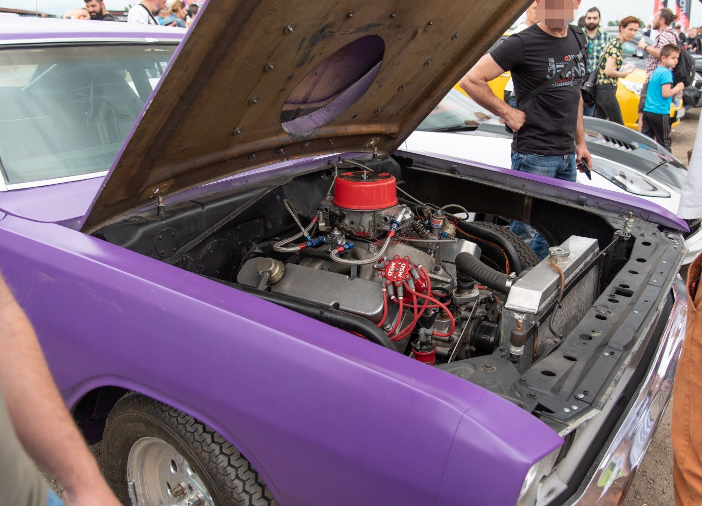 High-performance engine with custom parts under open hood of vintage muscle car.