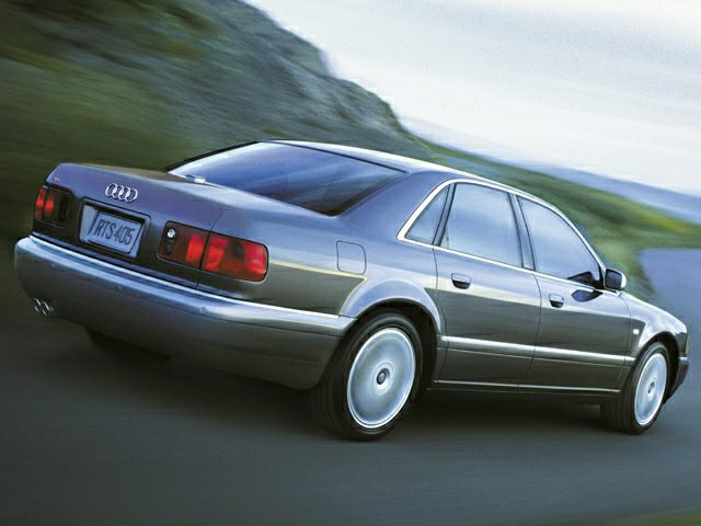 Rear three-quarter view of a silver luxury sedan with classic 90s design
