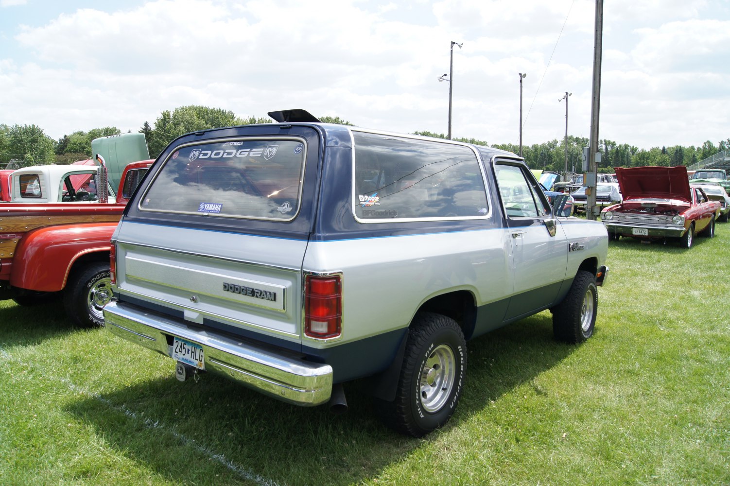 Rear and side view of a two-tone vintage SUV with off-road tires and rear window stickers