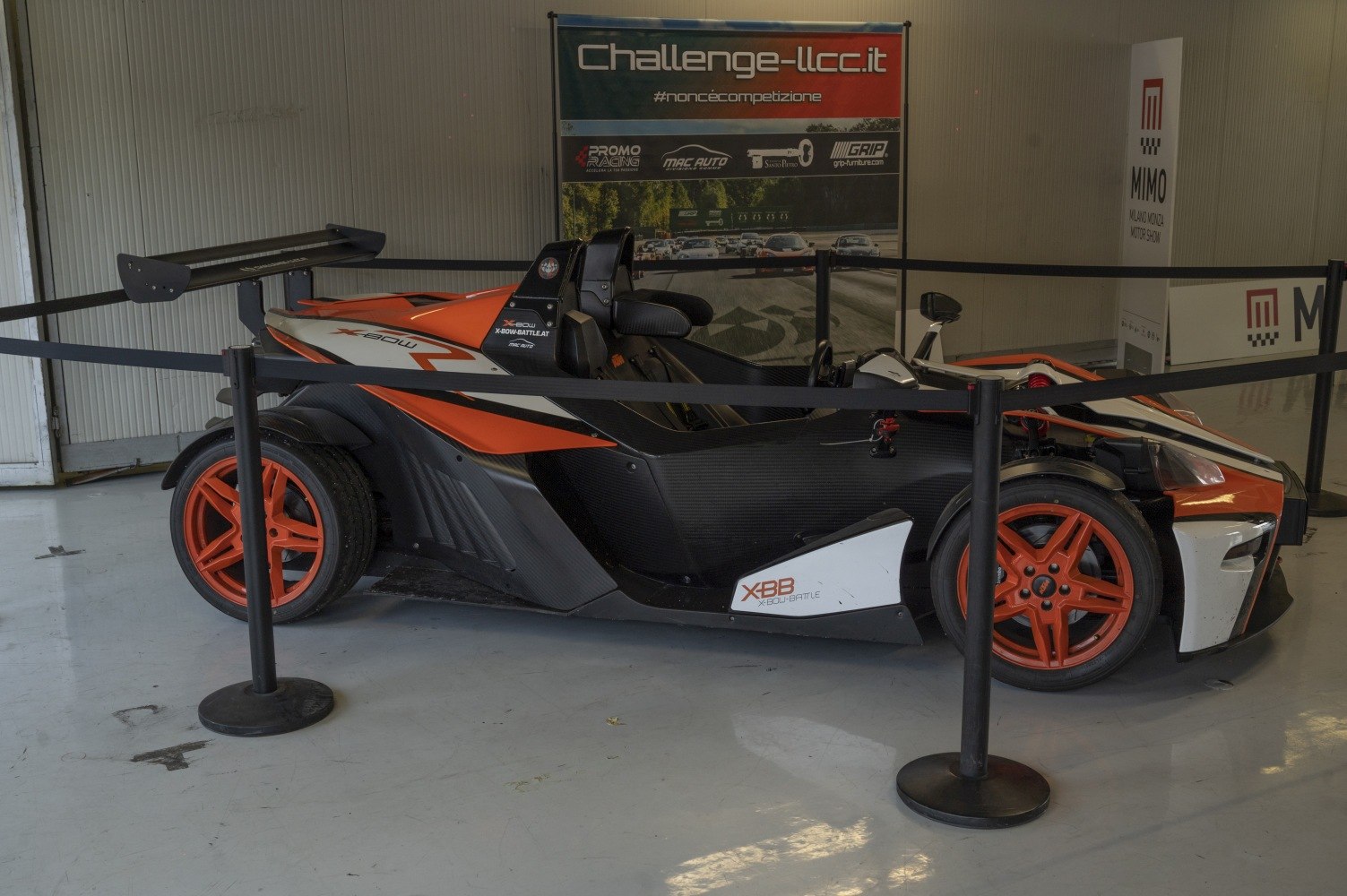 Side view of a race car with a prominent rear wing and orange wheels