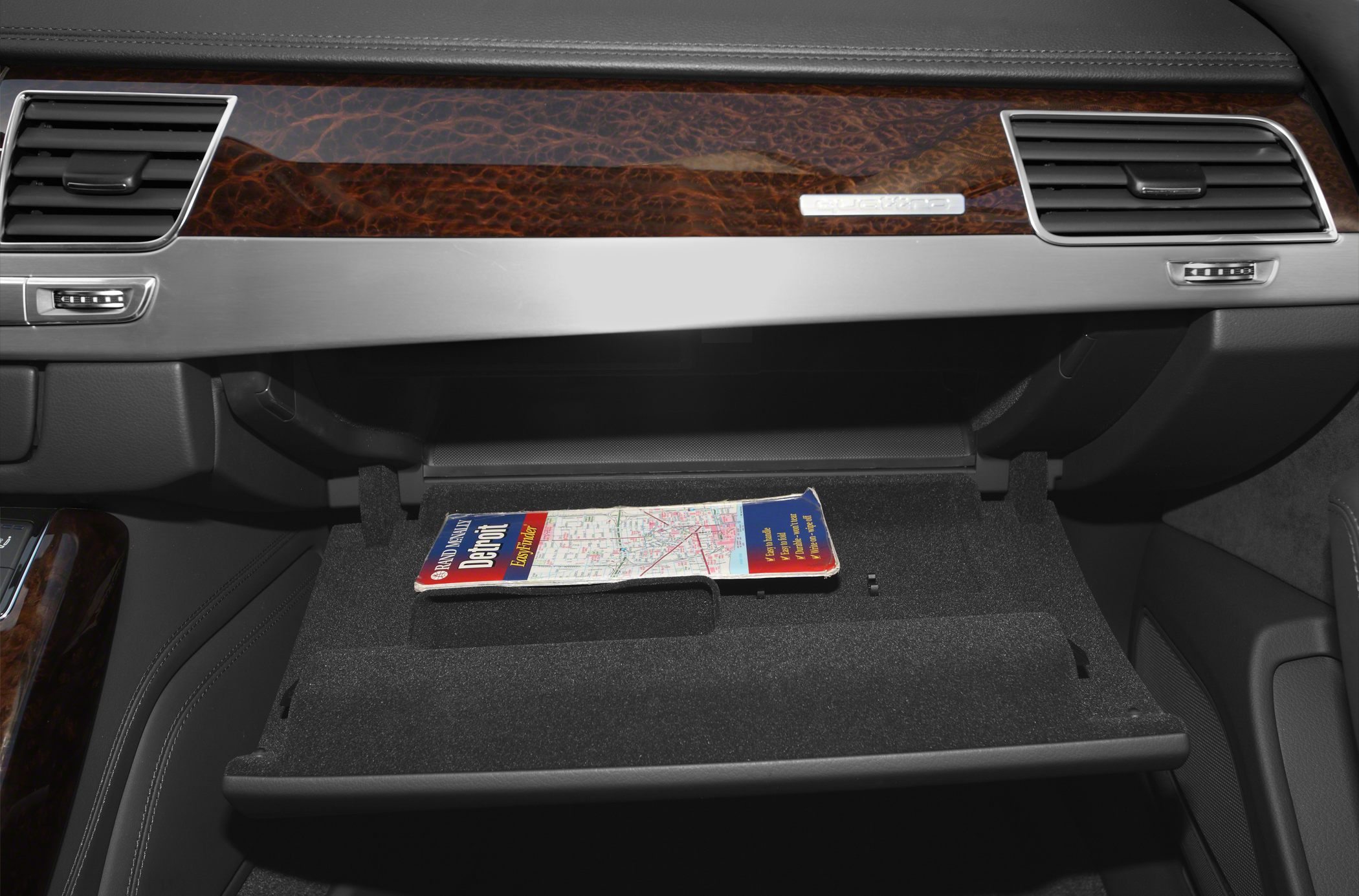 Wood trim dashboard and open glove compartment with map inside luxury vehicle