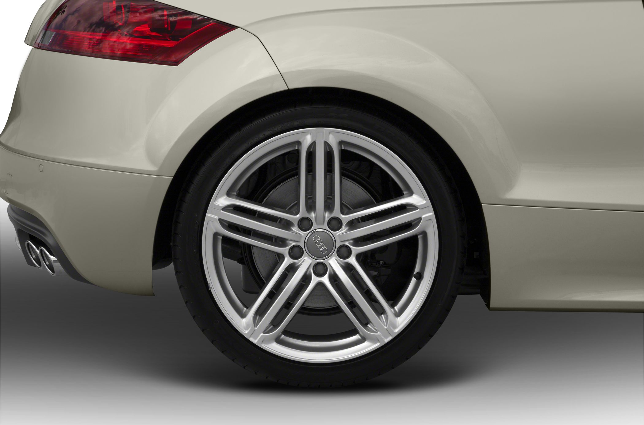 Close-up of rear wheel and tail light with alloy rim and dual exhaust