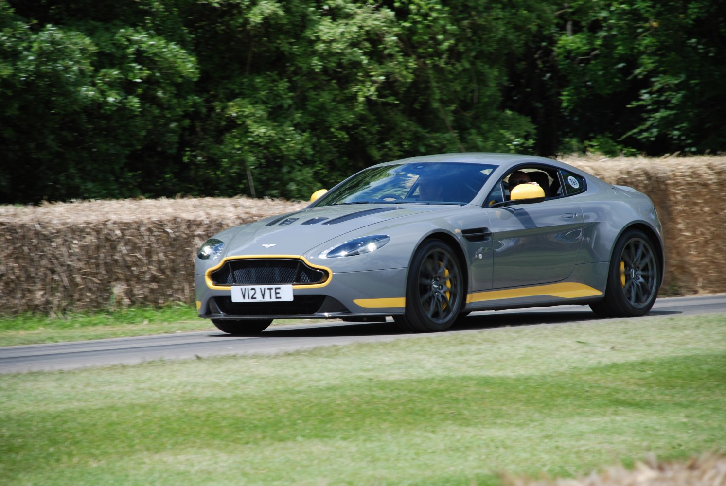 Sports coupe with yellow accents and aerodynamic design in motion on track.