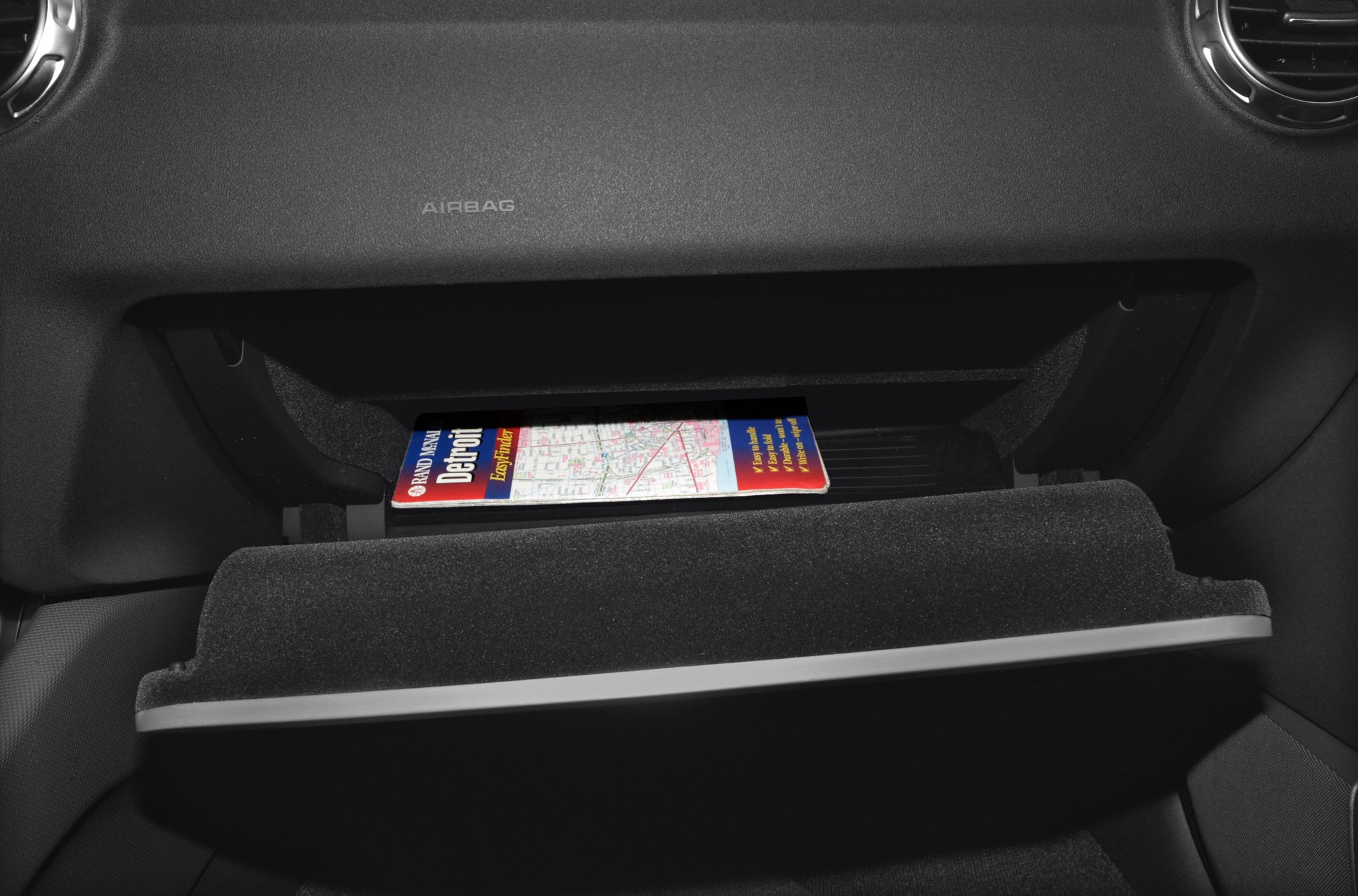 Open glove compartment with a map inside on a textured dashboard
