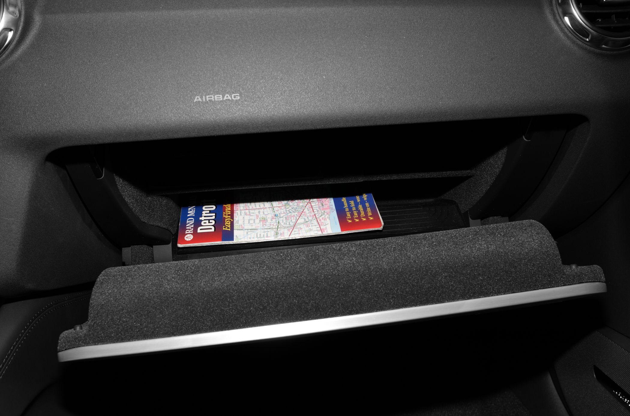 Open glove compartment with map inside and airbag label