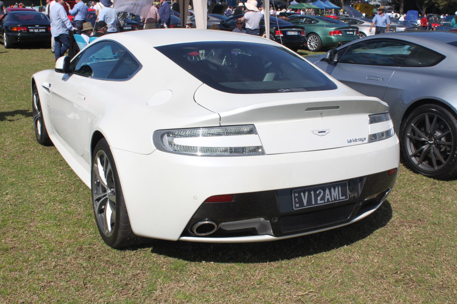 Rear view of white luxury coupe with distinctive tail lights and exhaust.