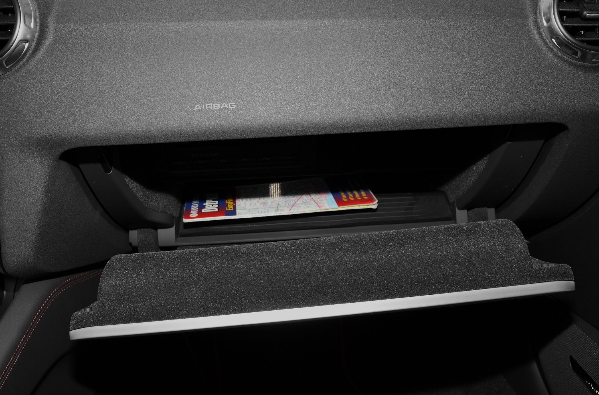 Glove compartment open with map inside, airbag label visible