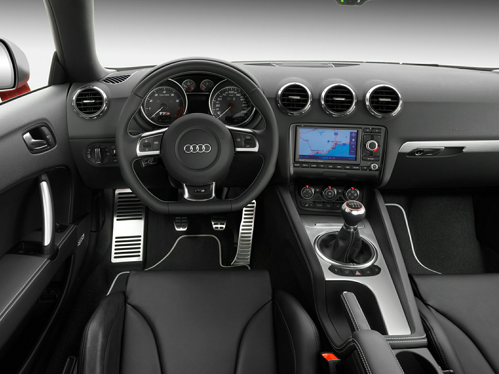 Dashboard, steering wheel, manual gear shifter, round air vents