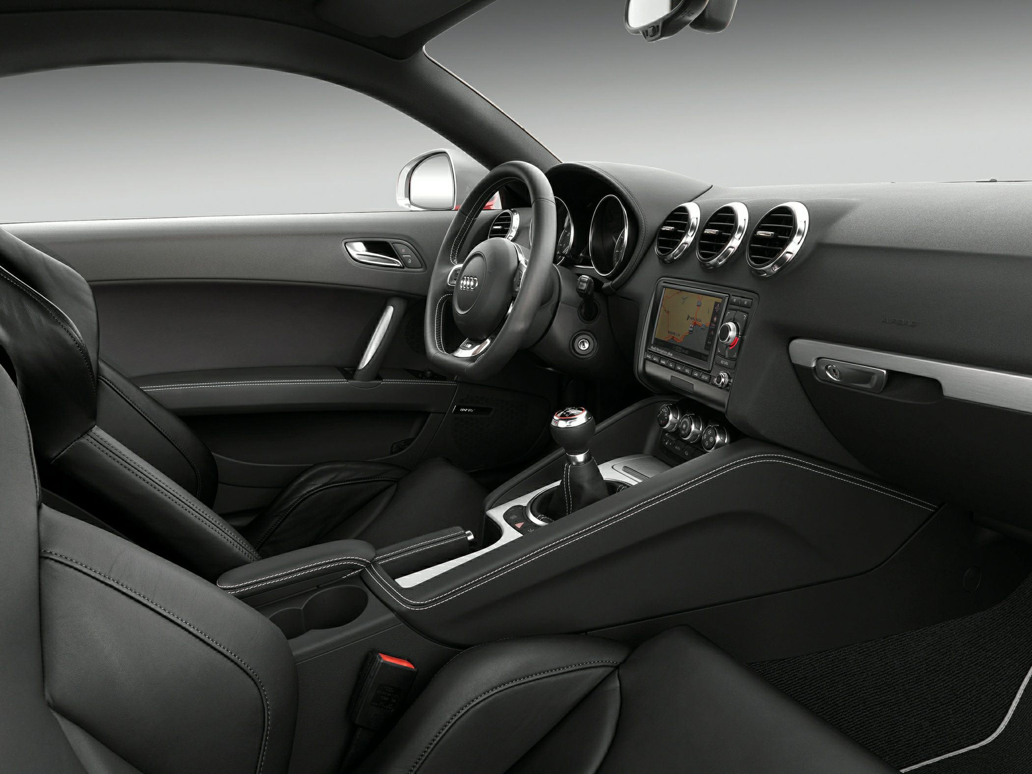 Sporty car interior with leather seats, circular air vents, and manual transmission