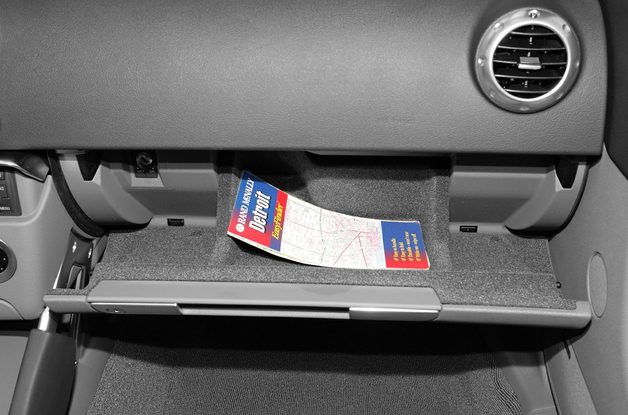 Open glove compartment with map inside car interior