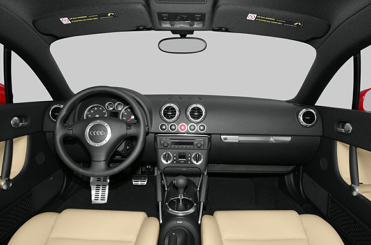 Dashboard, steering wheel, round air vents, beige seats, gear shift