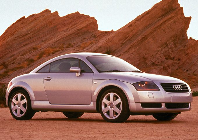 Silver compact coupe with rounded body and alloy wheels in desert.