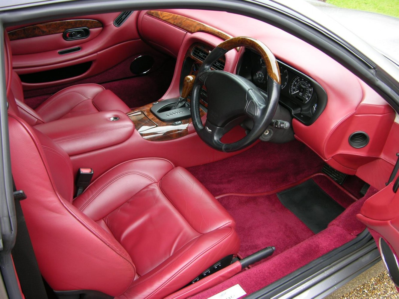 Luxurious red leather interior with wood trim and automatic gear shift
