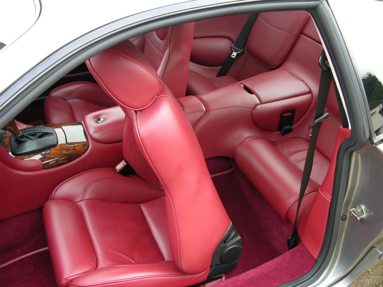 Red leather luxury car interior with wood trim and sporty seats