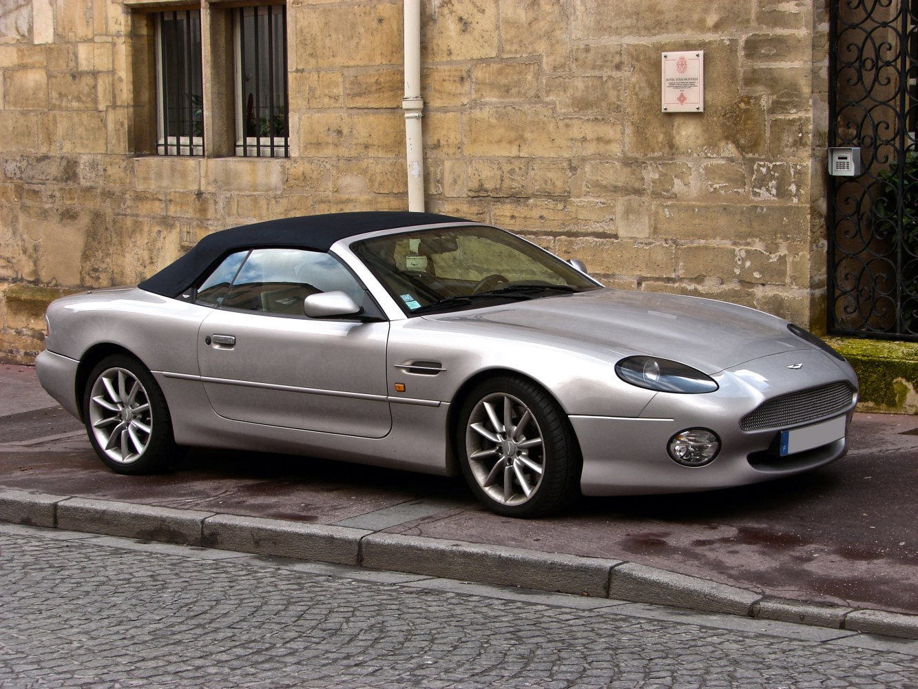 Silver convertible with soft black top parked on street